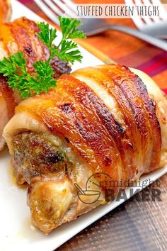 two pieces of meat sitting on top of a white plate next to a green garnish