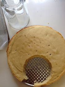 a sink with a strainer on the side and a bottle in the back ground