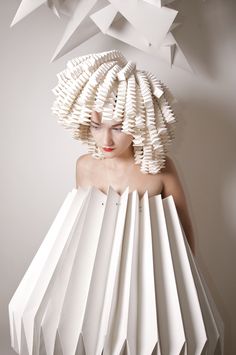 a woman with white hair and paper sculptures on her head