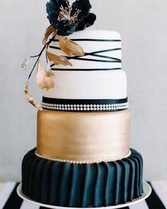 a three tiered cake with black, white and gold decorations on it's side