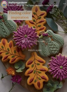 some cookies that are on a plate with flowers and leaves in the middle one is purple