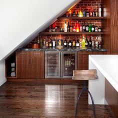 an attic bar with lots of bottles on the shelves and under the stairs is a white stair case