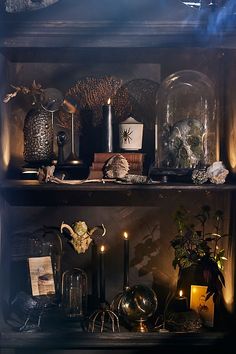 a shelf filled with candles and other items on top of it's shelves in a dark room