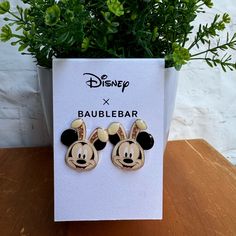 a pair of mickey mouse ear pins sitting on top of a wooden table next to a potted plant