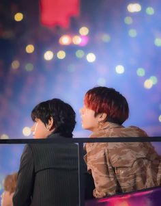 two people sitting next to each other on a bench in front of fireworks at night