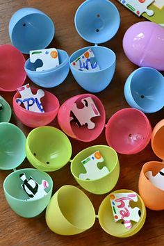 many different colored bowls and spoons on a wooden table with paper cut outs in the shape of animals