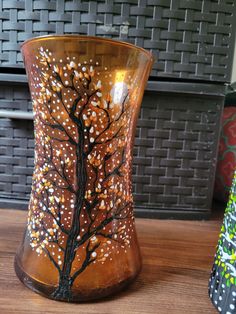 two vases sitting on top of a wooden table next to each other, one with a tree painted on it