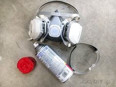 a gas mask sitting on the ground next to a can of paint