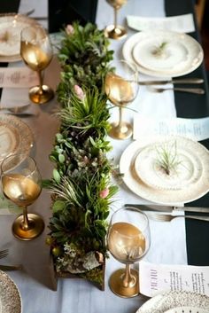 the table is set with plates, silverware and greenery for an elegant look