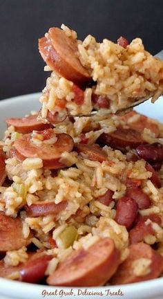 a spoon full of rice with sausage and beans