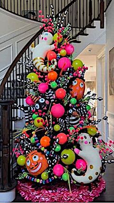 a decorated christmas tree in front of a spiral staircase with halloween decorations on the top