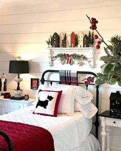 a bed with white sheets and red pillows in a room filled with christmas decorations on the wall