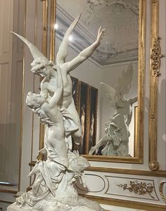 a statue is shown in front of a mirror with an angel on it's back