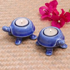 two blue tea lights sitting on top of a table next to pink flowers and a red flower