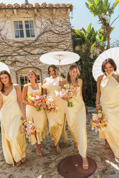 the bridesmaids are all dressed in yellow dresses and holding umbrellas over their heads