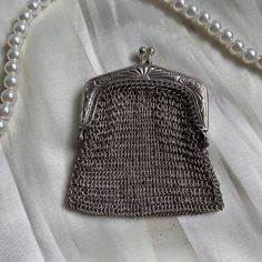 a chainmail purse with pearls on the bottom is laying on a white fabric background