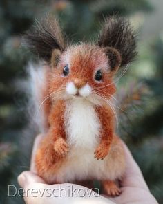 a small red squirrel sitting on top of someone's hand