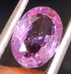 a pink diamond sitting on top of a person's finger