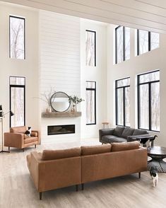 a living room filled with lots of furniture next to large windows on top of a hard wood floor