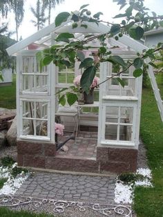 a small white greenhouse with lots of windows