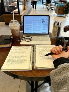 a person sitting at a table with a notebook and pen in front of a laptop