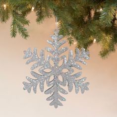 a silver snowflake ornament hanging from a christmas tree