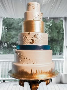 a multi layer cake sitting on top of a wooden table next to a white curtain