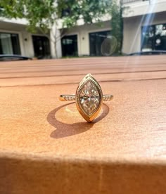 a diamond ring sitting on top of a wooden table in front of a storefront