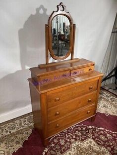 an old dresser with a mirror on top and rugs in the floor next to it