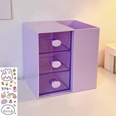 a purple box with three drawers on the inside and two white circles in the middle