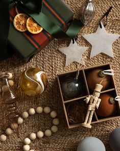 an assortment of christmas ornaments and decorations on a wicker tablecloth with oranges