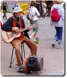 a man sitting on top of a chair while playing a guitar and singing into a microphone