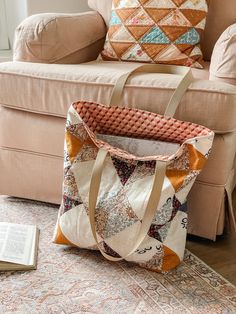 a bag sitting on top of a rug next to a couch with pillows and a book