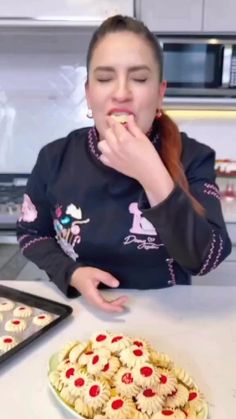 a woman sitting at a kitchen table eating food from a tray and muffins on the counter