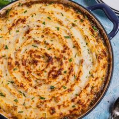 a large skillet filled with cheesy potatoes on top of a blue table