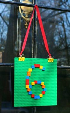 a bag made out of legos hanging from a window sill with the letter c on it