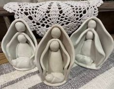 three ceramic figurines sitting on top of a table next to a doily