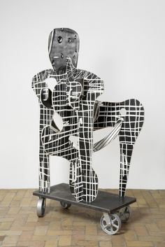 a black and white sculpture sitting on top of a skateboard in front of a wall