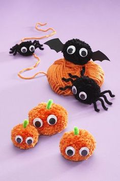 crocheted pumpkins with googly eyes and bats hanging from the string on purple background