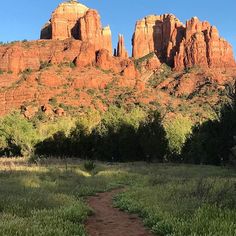 a dirt path in front of red rock formations