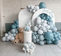 a teddy bear is sitting in front of some balloons and other decorations on the floor