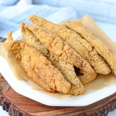 fried chicken sticks sitting on top of a white plate next to a blue and white napkin