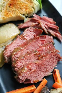 corned beef, carrots and cabbage on a black plate