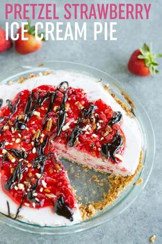 a cheesecake topped with strawberries and chocolate sauce on a glass pie plate next to sliced strawberries