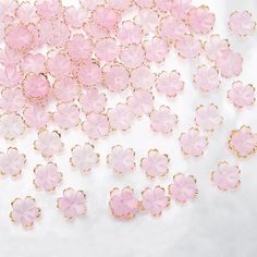 many pink flowers are shown on a white surface with gold chains and clasps around them