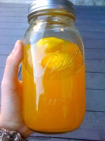 a hand holding a mason jar filled with orange juice