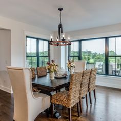 a dining room table with chairs and a chandelier in front of large windows