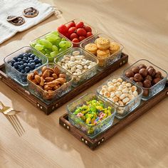 two trays filled with different types of food on top of a wooden table next to utensils