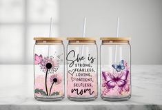 three mason jars with flowers and butterflies painted on them, sitting on a marble countertop