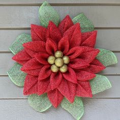 a red and green christmas wreath hanging on the side of a building with burlocks